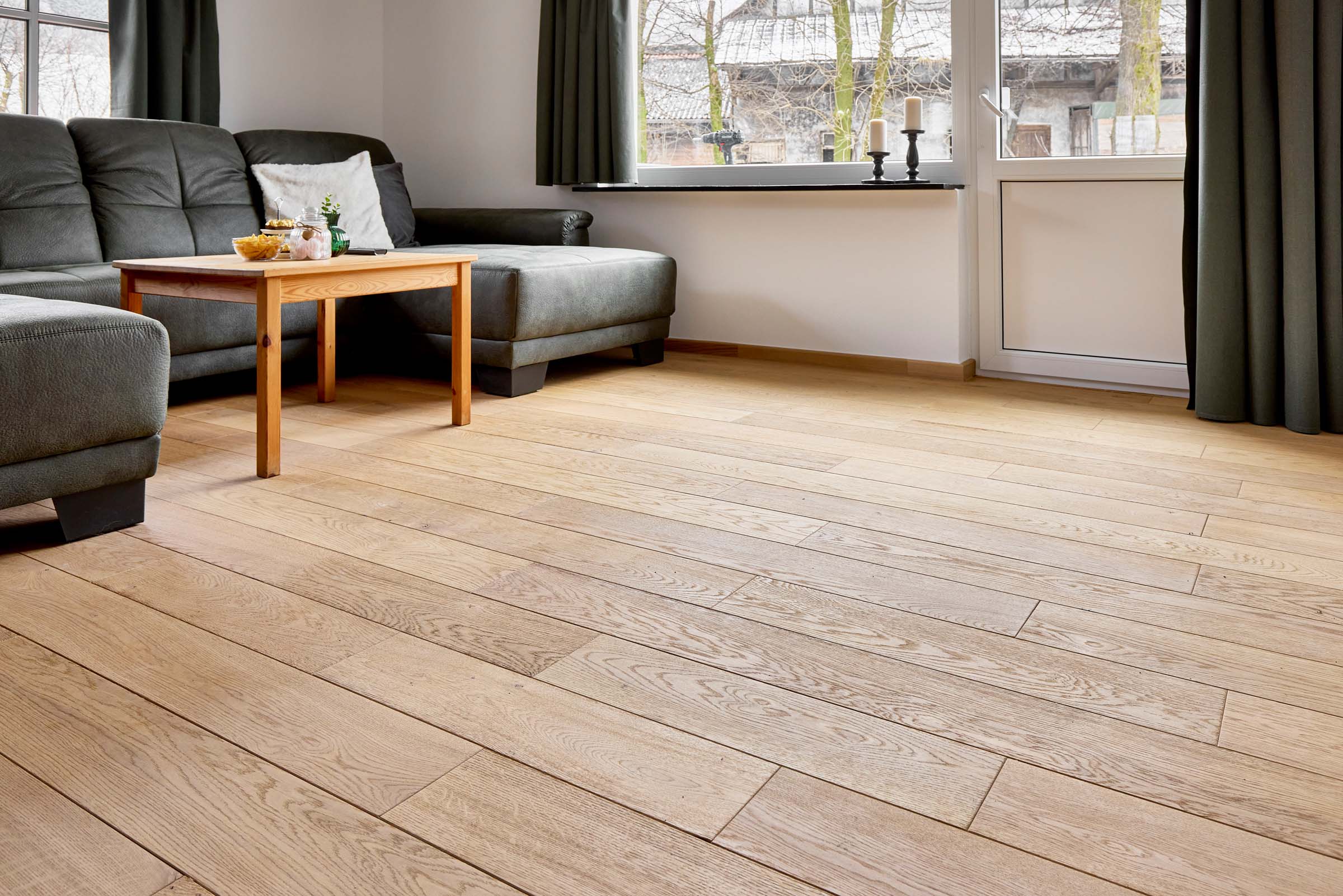 Helles Wohnzimmer mit großformatigen Eichedielen und abgestimmter Sockelleiste – natürlicher Bodenbelag im modernen Landhausstil.
