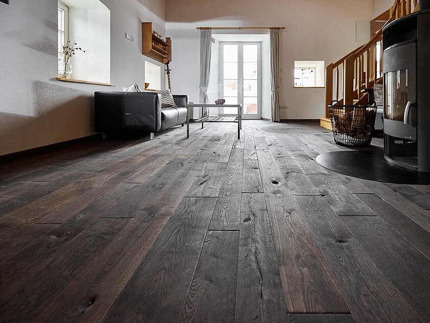 Mühlenboden im modernisierten Mühlenzimmer Wohnzimmer mit rustikalem Mühlenboden in dunkler Ausführung, moderner Einrichtung und Kaminofen in der renovierten alten Mühle.