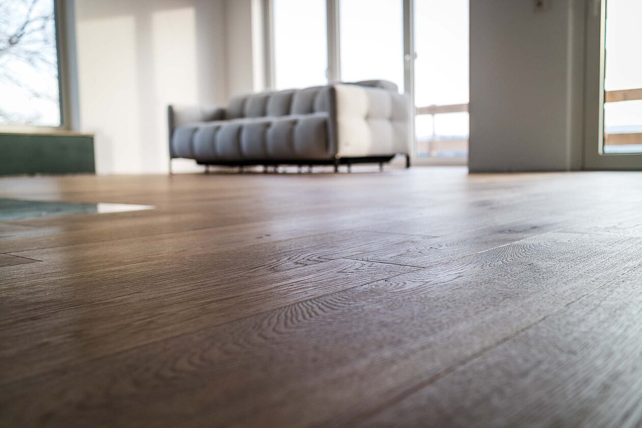 Helles Wohnzimmer mit natürlichem Holzboden in Eiche Weizen markant, modernes Interieur mit Couch und viel Tageslicht